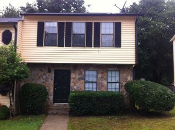 Marietta house for rent - a stone house with black shutters and a sidewalk