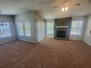 Fayetteville house for rent - an empty living room with a fireplace and a ceiling fan