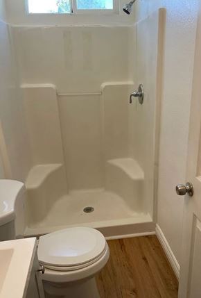 San Bernardino apartment for rent - A white toilet sits next to a white bathtub in a bathroom.