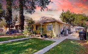 Riverside apartment for rent - a small yellow house with a yard and a tree