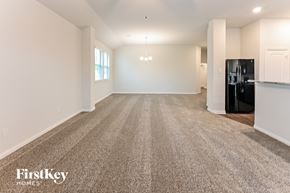 Cleveland house for rent - A spacious, empty room with a carpeted floor and a black refrigerator in the corner.