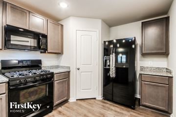 Splendora house for rent - A kitchen with a black fridge and a black stove top oven.