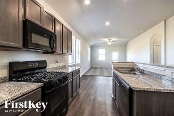 Splendora house for rent - A kitchen with dark wood cabinets and granite countertops.