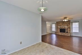 Abilene house for rent - A spacious room with a fireplace and a ceiling fan.
