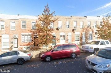 Baltimore house for rent - a parking lot with cars in front of a brick building