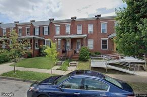 Baltimore house for rent - a car parked in front of a brick building