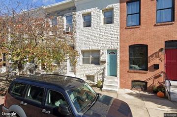 Baltimore house for rent - a car parked in front of a white house