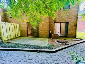 Dunwoody apartment for rent - A brick building with a door and windows is surrounded by a gravel area.