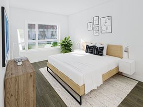 Winnipeg apartment for rent - A bedroom with a large bed, a wooden nightstand, and a plant.