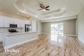 Lehigh Acres house for rent - A spacious kitchen and living room with wooden floors and a ceiling fan.