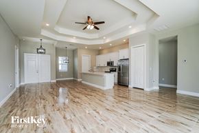 Lehigh Acres house for rent - A spacious kitchen with wooden floors and a ceiling fan.