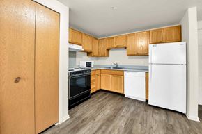 Utica apartment for rent - a kitchen with wooden cabinets and a white refrigerator