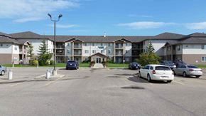 Red Deer apartment for rent - A parking lot in front of a building with cars parked.