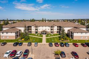 Red Deer apartment for rent - A large building with a parking lot in front of it.