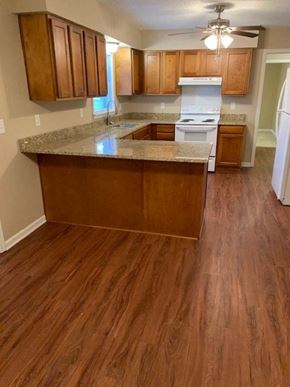 Hope Mills house for rent - A kitchen with wooden floors and a white fridge.