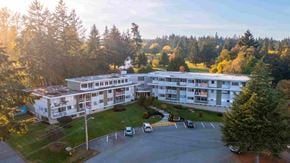 Nanaimo apartment for rent - A large white building with a parking lot in front of it.