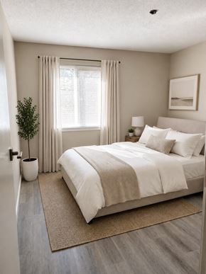 Nanaimo apartment for rent - A bedroom with a large bed and a potted plant.
