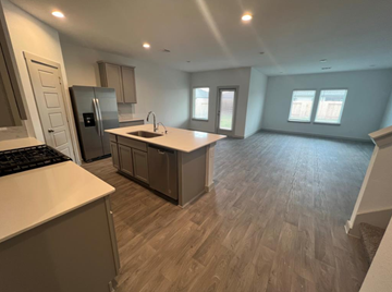 Rosharon house for rent - A kitchen with a refrigerator, sink, and cabinets.
