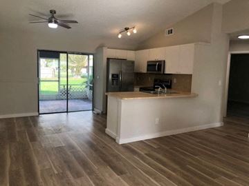 Port St. Lucie house for rent - A kitchen with a black fridge and microwave, a white counter, and a ceiling fan.