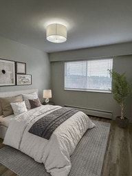 Nanaimo apartment for rent - A bedroom with a bed, pillows, a lamp, a plant, and pictures on the wall.