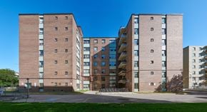 Toronto apartment for rent - A large brick building with a green lawn in front.