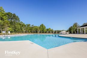 Greenville house for rent - A swimming pool surrounded by trees and a building in the background.