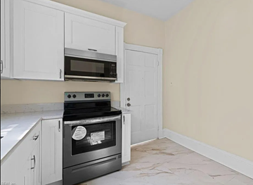 Portsmouth apartment for rent - a kitchen with white cabinets and a stove and a microwave