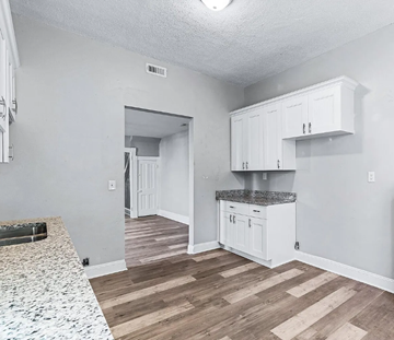 Portsmouth apartment for rent - A kitchen with white cabinets and a granite countertop.
