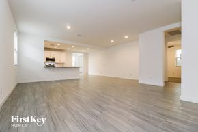 Glendale house for rent - A spacious empty room with wooden flooring and a kitchen visible through the open door.