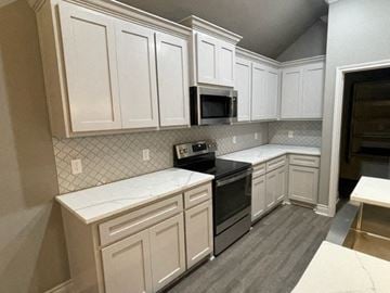 Greenville house for rent - A kitchen with white cabinets and a black stove top oven.