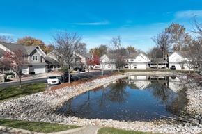 Indianapolis townhouse for rent - A residential street with houses on both sides and a pond in the foreground.