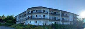 Nanaimo apartment for rent - A sunny day at a white apartment building with balconies.
