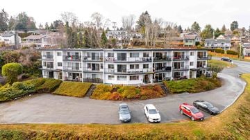 Nanaimo apartment for rent - A large white building with a parking lot in front.
