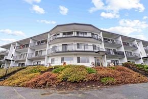 Nanaimo apartment for rent - A large white building with balconies and a red door.