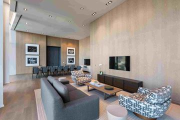 Honolulu apartment for rent - A modern living room with a grey sofa, a patterned armchair, and a television mounted on the wall.