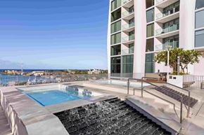 Honolulu apartment for rent - A modern building with a pool and a waterfall.