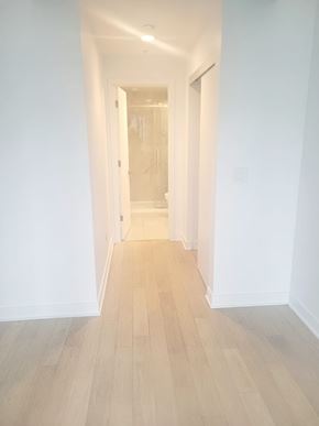 Montréal apartment for rent - A long hallway with white walls and wood flooring.