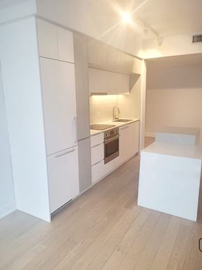 Montréal apartment for rent - A kitchen with white cabinets and a wooden floor.