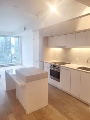 Montréal apartment for rent - A kitchen with white cabinets and a wooden floor.