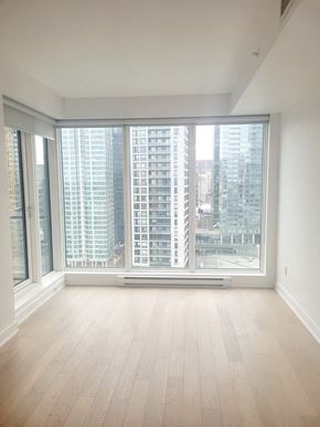Montréal apartment for rent - A large empty room with a view of a cityscape through the windows.