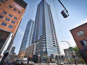 Montréal apartment for rent - A tall building with the logo "GEL" on the top stands in the middle of a city street.