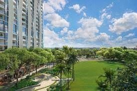 Honolulu apartment for rent - A view of a green lawn with trees and a building in the background.
