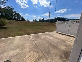 Collins apartment for rent - A concrete patio with a white fence and a grassy field in the background.