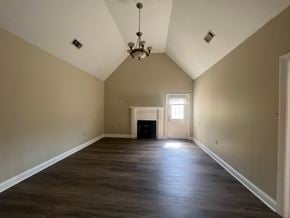Collins apartment for rent - A large empty room with a chandelier and a door at the end.