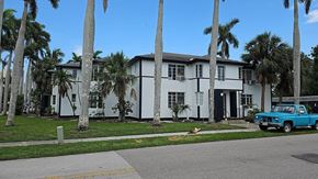 Fort Myers apartment for rent - A blue truck is parked in front of a white house with a black door.