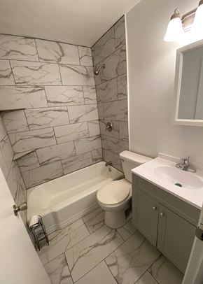 Clinton house for rent - A white toilet sits in a marble bathroom next to a sink.