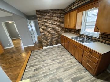 Clinton house for rent - A kitchen with wooden cabinets and a brick wall.
