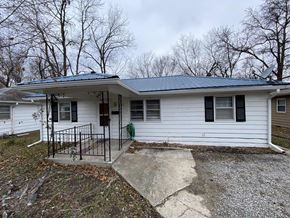 Clinton house for rent - A small white house with a black metal fence and a green hose on the front porch.
