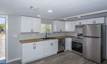 Tucson house for rent - A kitchen with white cabinets and a wooden counter.
