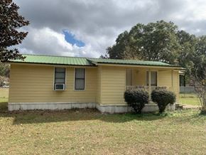Crestview house for rent - a yellow house with a green roof and some bushes